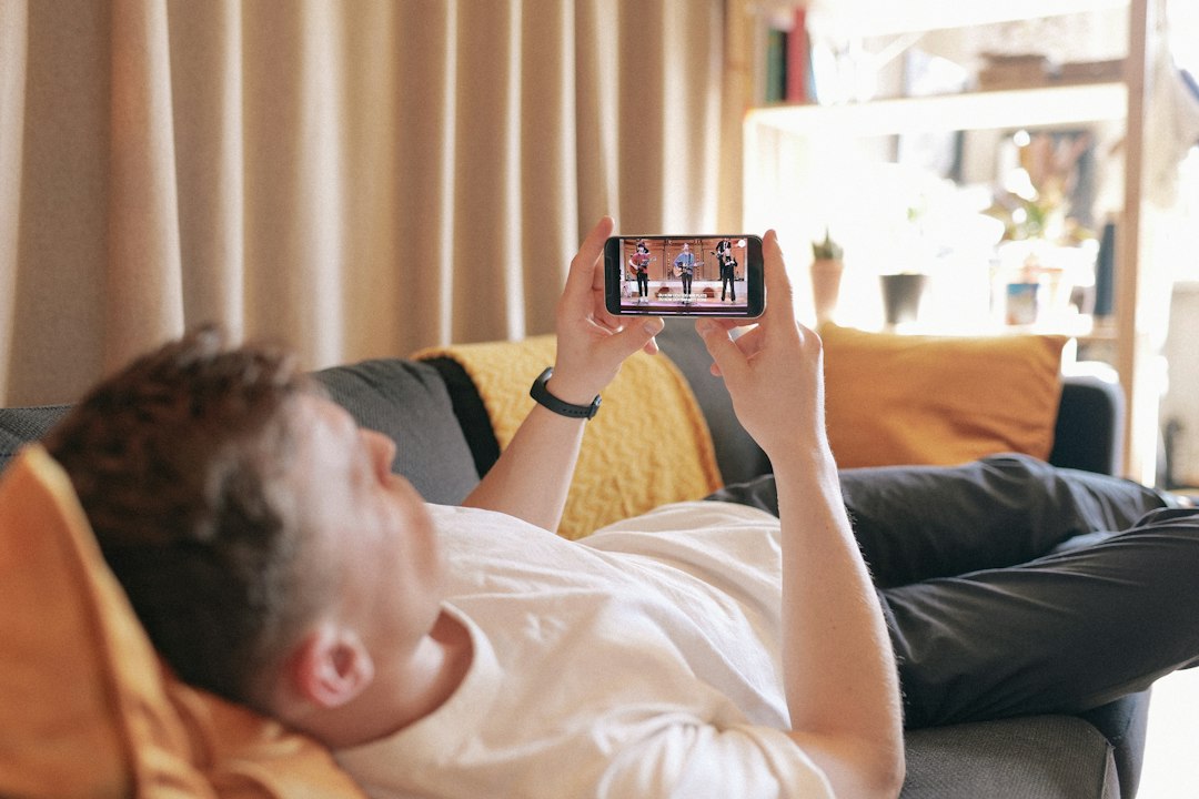 ベッドでスマホを見て横たわる人 — 言い訳で認知的不協和を解消し習慣が続かないイメージ