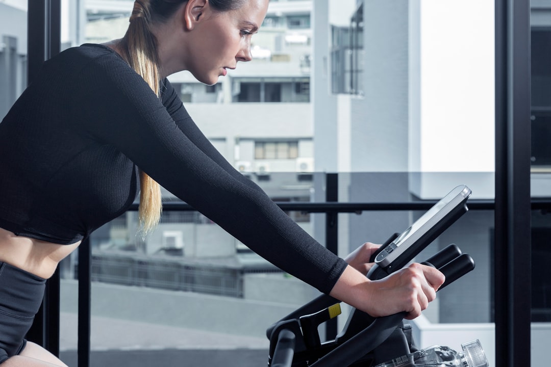 誘惑バンドリングのイメージ — エアロバイクをこぎながらタブレットで動画を見る女性