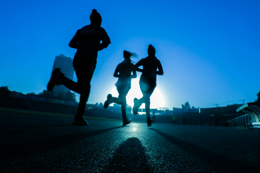 運動は朝と夜どっちがいいか考える人のイメージ — 道路を走る3人のランナーのシルエット