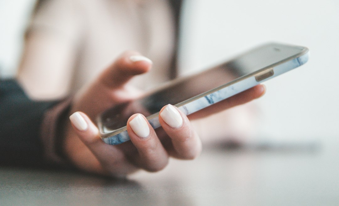 スマートフォンを操作する手 — Notionと専用の習慣化アプリを比較するイメージ