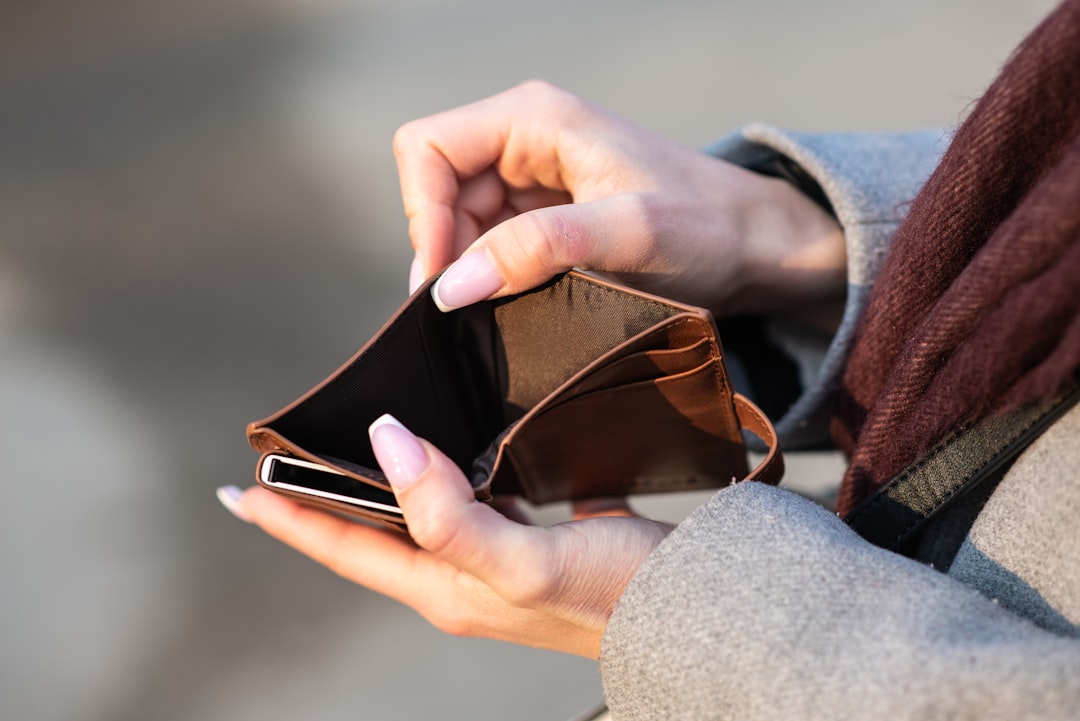 硬貨が出ていく空の財布とスマホ。貯金が続かず手元にお金が残らないイメージ
