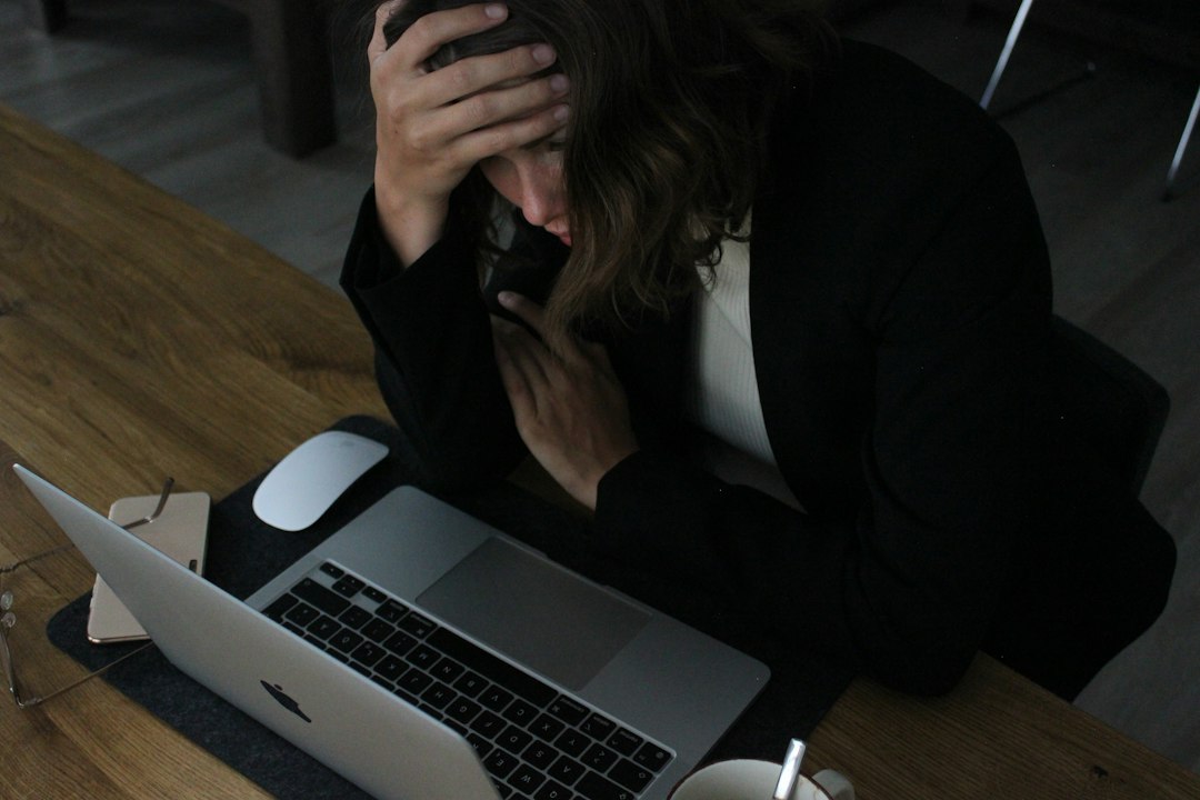 仕事と勉強の両立に悩む社会人 — ノートパソコンの前で頭を抱える様子